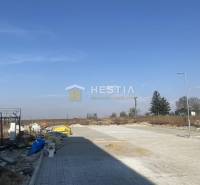 Posledný byt!! NA PREDAJ novostavba, 3-izb.byt, Petrova Ves - Stavba a exteriér s prázdnym pozemkom, modrá obloha, v pozadí stromy.