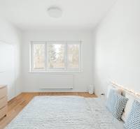 NUERA | PREDAJ 4i byt s predzáhradkou pri lese + 2x parking , BAIV - Svetlá spálňa v 4-izbovom byte s podlahou s dreveným dekorom a dekoratívnymi vankúšmi.