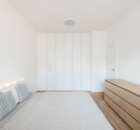 NUERA | PREDAJ 4i byt s predzáhradkou pri lese + 2x parking , BAIV - Svetlá spálňa v 4-izbovom byte s posteľou, vankúšmi a skriňou, podlaha s dreveným dekorom.