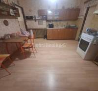 Na predaj rodinny dom v obci Iža. - Kuchyňa s plynovým sporákom, podlahou s dreveným dekorom a jedálenským stolom v rodinnom dome.