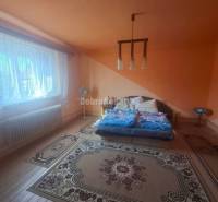 Na predaj rodinny dom v obci Iža. - Podkrovná spálňa v Rodinnom dome s farebnými stenami a dreveným dekorom podlahy.