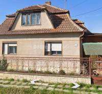 Na predaj rodinny dom v obci Iža. - Rodinný dom v Iži s tradičnou strechou a kvetinovým plotom.