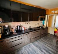 Na predaj 3-podlažný rodinný dom  v blízkosti centra Myjavy  - Kuchyňa s čiernymi skrinkami a podlahou s dreveným dekorom v rodinnom dome.