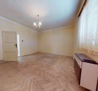 Rodinný dom v obci Belince - Izba v rodinnom dome s podlahou s dreveným dekorom a jednoduchým lustrom.