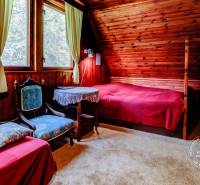 Dvojpodlažná chata v krásnom prostredí Buková, okr. Trnava - Izba v Chate s dreveným obkladom, posteľou a kreslom, príjemná atmosféra na oddych.