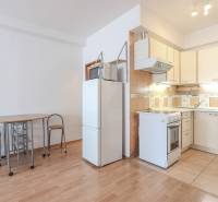 Na prenájom 2 izbový byt v Piešťanoch - Kuchyňa v 2-izbovom byte s podlahou s dreveným dekorom, jedálenským stolom a chladničkou.