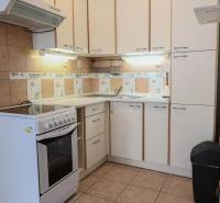 Na prenájom 2 izbový byt v Piešťanoch - Kuchyňa v 2-izbovom byte s bielymi skrinkami a sporákom, podlaha s dreveným dekorom.