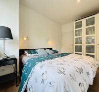 Tichý 2i byt v TOP Lokalite Nív | Trenčianska, BA - Spálňa s pohodlnou posteľou a skriňou v 2-izbovom byte s podlahou s dreveným dekorom.