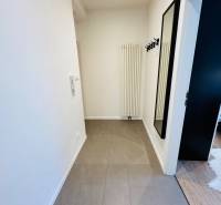 Tichý 2i byt v TOP Lokalite Nív | Trenčianska, BA - Chodba v 2-izbovom byte s dlažbou, vešiakmi a kachľovým radiátorom.