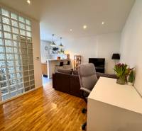 Tichý 2i byt v TOP Lokalite Nív | Trenčianska, BA - Obývacia izba v 2-izbovom byte s presklenou stenou a podlahou s dreveným dekorom.