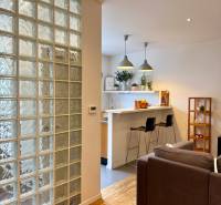 Tichý 2i byt v TOP Lokalite Nív | Trenčianska, BA - Obývačka s podlahou s dreveným dekorom a kuchynským barovým pultom v 2-izbovom byte.