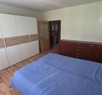 Prenájom veľký 1 izbový byt 48m2 Vráble- Centrum - Spálňa v 1-izbovom byte s podlahou s dreveným dekorom a praktickým nábytkom.