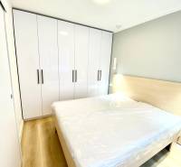 Dizajnový moderný 2 izbový byt Jurigovo nám. Bratislava IV Karlova Ves - Spálňa s manželskou posteľou, bielou skriňou a podlahou s dreveným dekorom v 2-izbovom byte.