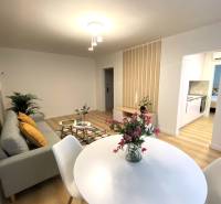 Dizajnový moderný 2 izbový byt Jurigovo nám. Bratislava IV Karlova Ves - Jedáleň v 2-izbovom byte s bielym stolom a podlahou s dreveným dekorom.