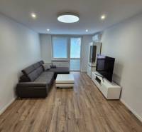 Prenájom 2-izbového bytu Bratislava II, Ružinov - Obývačka v 2-izbovom byte so sedačkou, stolíkom a televízorom na drevenej podlahe.