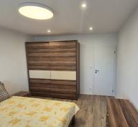 Prenájom 2-izbového bytu Bratislava II, Ružinov - Spálňa v 2-izbovom byte s podlahou s dreveným dekorom a veľkou skriňou.