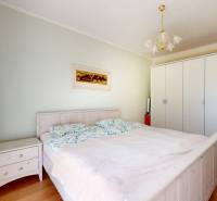 4-izbový dom 132m2 + pozemok 484m2 | Bernolákovo - Svetlá spálňa s manželskou posteľou, skriňami a podlahou s dreveným dekorom v rodinnom dome.