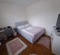 Predaj čiastočne prerobený 3 izbový byt Martin Sever - Spálňa v 3-izbovom byte s podlahou s dreveným dekorom, posteľou a televízorom na skrinke.