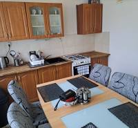 Predaj čiastočne prerobený 3 izbový byt Martin Sever - Kuchyňa s jedálenským stolom v 3-izbovom byte, drevené skrinky a sporák.