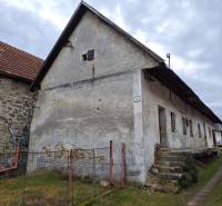Rodinný dom v obci Háj v pôvodnom stave s veľkým potenciálom - Záber staršieho rodinného domu v Háji so schodmi a záhradou, obloha zachmúrená.