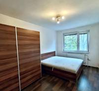 Predaj 4-izbového bytu na začiatku Petržalky Bratislava V - Spálňa so skriňou, posteľou a podlahou s dreveným dekorom v 4-izbovom byte.