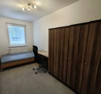 Predaj 4-izbového bytu na začiatku Petržalky Bratislava V - Izba v 4-izbovom byte s posteľou, stolom, stoličkou a skriňou na koberci.