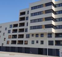 KÚPA GARÁŽE V PEZINKU - Budova s garážami na ulici Dona Sandtnera v Pezinku, svetlá fasáda s tmavými oknami.