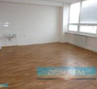 PRENÁJOM KANCELÁRSKÝCH PRIESTOROV NA RAČIANSKEJ ULICI - Prázdna miestnosť s umývadlom, drevená podlaha, veľké okná na ulici Račianska.