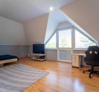 ,,,EXKLUZÍVNE,,,PREDAJ PRIESTRANNÉHO 5 IZB.RD V PEZINKU / LIMBACH - Podkrovná izba v rodinnom dome so stolom, posteľou a televízorom.