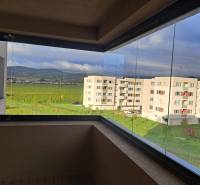 PREDAJ NADŠTANDARDNÉHO 4 IZB.BYTU V NOVOM KOMPLEXE-VINICE-150,18 m2 - Zasklený balkón ponúka výhľad na moderné budovy a zeleň, vhodný pre 4-izbový byt.