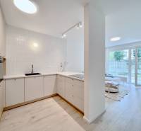 NUERA︱NOVÝ RUŽINOV - kompletne zariadený 2-izbový apartmán so záhradou - Kuchyňa s bielymi skrinkami, podlaha s dreveným dekorom, otvorený priestor v 2-izbovom byte.