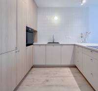 NUERA︱NOVÝ RUŽINOV - kompletne zariadený 2-izbový apartmán so záhradou - Kuchyňa v 2-izbovom byte s podlahou s dreveným dekorom, bielymi skrinkami a vstavanou rúrou.