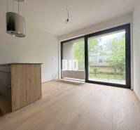 Posledný voľný APARTMÁN na kľúč - Rajecké Teplice - Interiér 2-izbového bytu s drevenou podlahou a veľkým oknom na zelený exteriér.