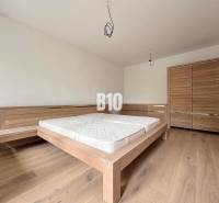 Posledný voľný APARTMÁN na kľúč - Rajecké Teplice - Spálňa v 2-izbovom byte s drevenou posteľou a skriňou na drevenej podlahe.
