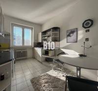 Sad na Studničkách - 2 izbový byt 60m2 - Kuchyňa v 2-izbovom byte s bielymi skrinkami, oknom a jedálenským stolom.