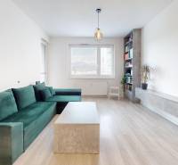 Na predaj 2-izbový byt v novostavbe s parkingom, Na pažiti, Trenčín - Obývačka v 2-izbovom byte s pohovkou, stolom a podlahou s dreveným dekorom.