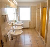 Na prenájom zrekonštruovaná ubytovňa s garážami a skladovacími kobkami - Kúpeľňa v budove ponúka umývadlá a sprchy s kachličkovou podlahou.