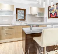 2-izb. byt v RD, TERASA, BA IV Dúbravka, Tavarikova Osada - Kuchyňa v 2-izbovom byte so svetlými skriňami, barovým pultom a obrazom na stene.