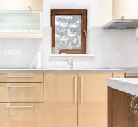 2-izb. byt v RD, TERASA, BA IV Dúbravka, Tavarikova Osada - Kuchyňa v 2-izbovom byte s dreveným oknom, svetlými skrinkami a sivými dlaždicami.