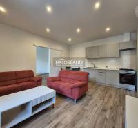 REZERVOVANÉ - Predaj, dvojizbový byt Lučenec - EXKLU... - Obývačka v 2-izbovom byte s podlahou s dreveným dekorom, červené sedačky, kuchyňa.