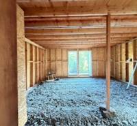 Chata pred dokončením, pozemok 770 m2, Horná Maríková - Rozostavaný interiér chaty s drevenou konštrukciou a otvorom na terasu.