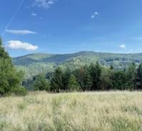 Chata pred dokončením, pozemok 770 m2, Horná Maríková - Horská krajina pri Hornej Marikovej s lúkou a lesmi pod modrou oblohou.