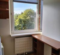 Prenájom 1-izbového bytu s energiami, Martin - Jahodníky - Malý pracovný kút so stolom, podlahou s dreveným dekorom a výhľadom na zeleň.