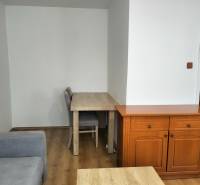 Prenájom 1-izbového bytu s energiami, Martin - Jahodníky - Interiér 1-izbového bytu so sedačkou, stolom a podlahou s dreveným dekorom.