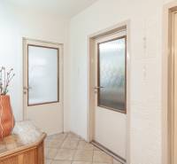 Predaj 3i bytu 84m2 - dva balkóny , Nábrežná v NZ - Chodba v 3-izbovom byte s kvetinou na drevenom stolíku a dverami s sklom.