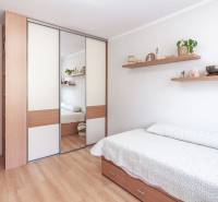 Predaj 3i bytu 84m2 - dva balkóny , Nábrežná v NZ - Spálňa v 3-izbovom byte s posteľou a zrkadlovou skriňou, podlaha s dreveným dekorom.