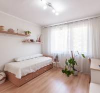 Predaj 3i bytu 84m2 - dva balkóny , Nábrežná v NZ - Svetlá izba s posteľou, písacím stolom a podlahou s dreveným dekorom v 3-izbovom byte.