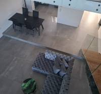 Moderný rodinný dom so záhradou, bazénom a nadštandardným priestorom - Interiér rodinného domu s pohľadom na jedálenský stôl, sedačku a schodisko.