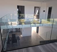 Moderný rodinný dom so záhradou, bazénom a nadštandardným priestorom - Interiér rodinného domu s preskleným zábradlím a podlahou s dreveným dekorom.