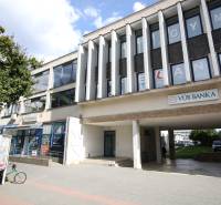 Prenájom centrum Galanty - Budova s kanceláriami a bankou v Galante, so stromom a chodníkom v popredí.